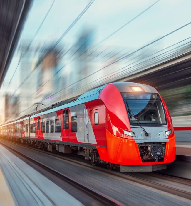 Electric passenger train drives at high speed among urban landscape